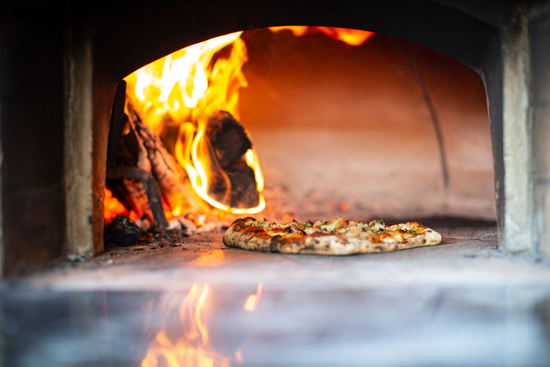 Wood-fired pizza oven built into a custom outdoor kitchen